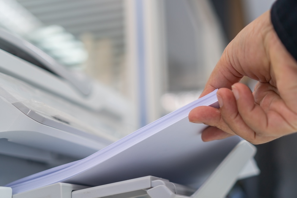 Business printer / printing documents in office concept: Picking up documents from the printer.