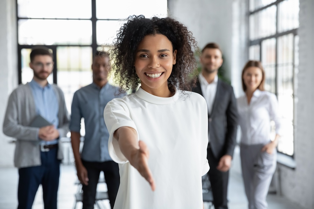 smiling businesswoman offering handshake, standing with extended hand in modern office. concept of finding the right MPS partner.