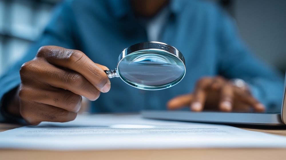 man using a magnifying glass to review print costs more closely